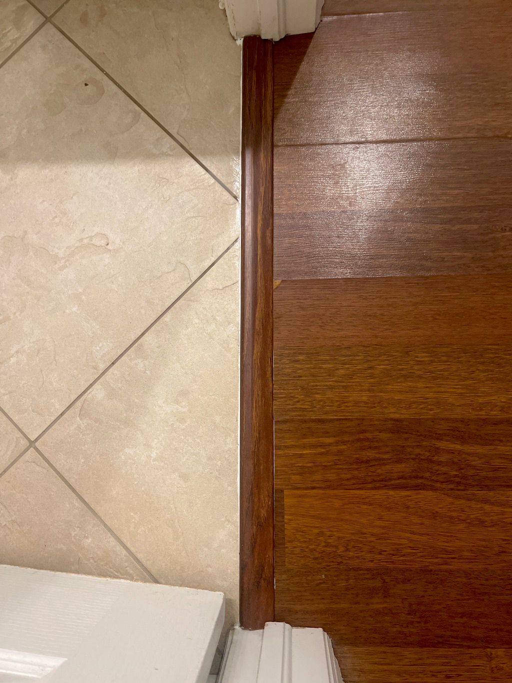 Finished transition strip fitted between tile and wood flooring
